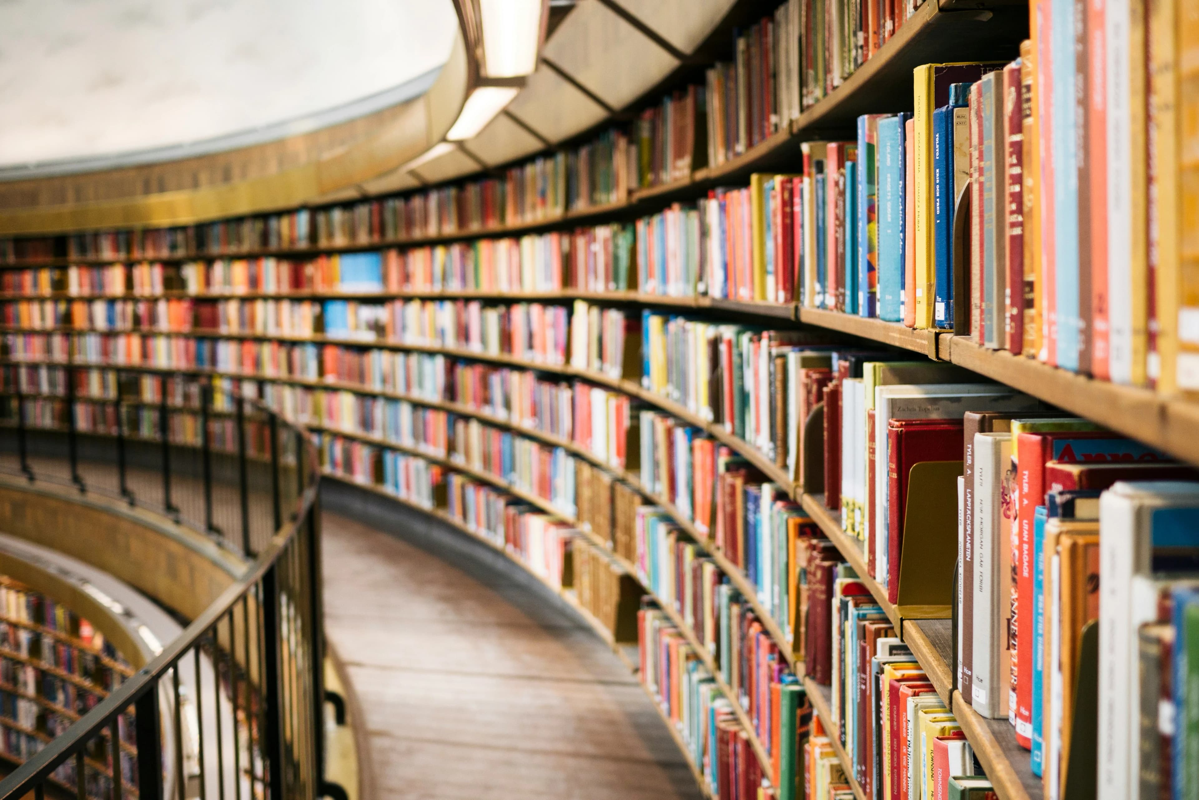 Rak buku melengkung berisi punggung buku berwarna-warni